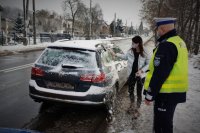 Kobieta odśnieża samochód pod okiem policjanta drogówki