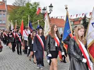 po ulicy maszerują delegacje sztandarowe, młodzież ma na sobie szarfy w barwach narodowych Polski
