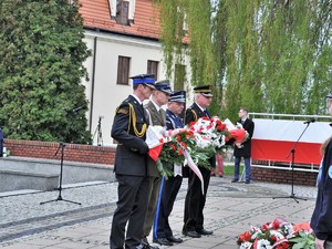 podczas uroczystości stoją obok siebie przedstawiciele służb mundurowych, składają kwiaty pod Pomnikiem Powstańców Śląskich