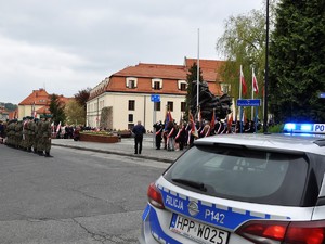na zdjęciu widać policyjny radiowóz, w dali widać trwające uroczystości pod Pomnikiem Powstańców Śląskich
