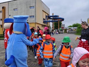 Na zdjęciu widać maskotkę witającą grupkę dzieci.