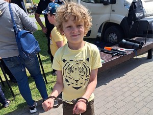 Na zdjęciu widać pozującego do zdjęcia chłopca z założonymi kajdankami