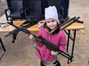 dziewczynka pozuje do zdjęcia z bronią długą