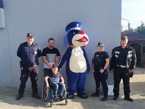 do wspólnego zdjęcia pozują policjanci i chłopiec siedzący na wózku inwalidzkim